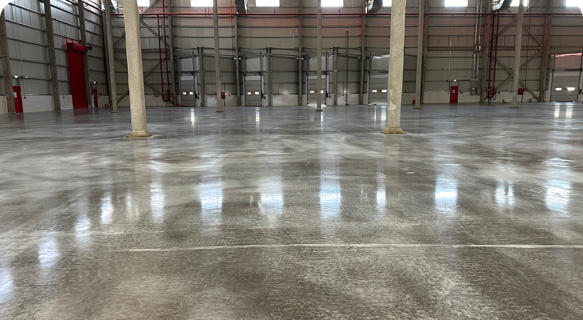 Empty warehouse interior with shiny concrete floor.